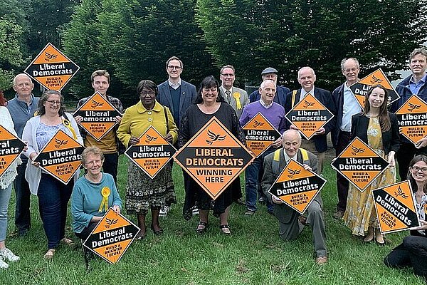 A crowd of Liberal Democrats hold Liberal Democrat gold diamond shaped posters