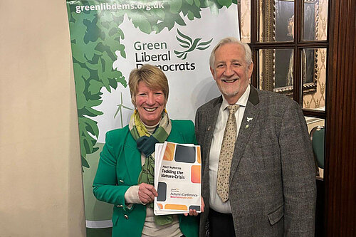 Pippa holding Tackling the Nature Crisis, with the chair of Green Lib Dems